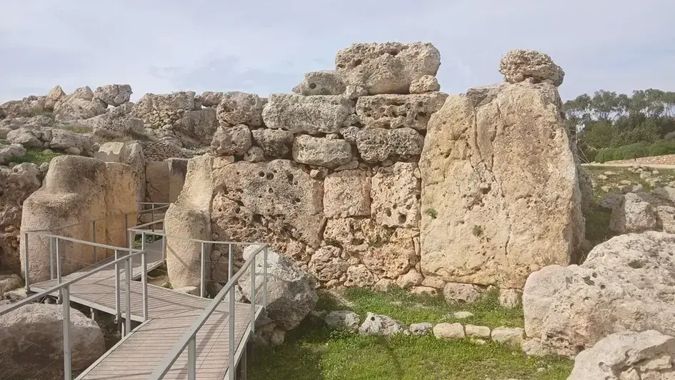 The visitor route passes between upright megaliths and carefully built interior walls.