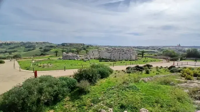 The monumental outer wall rises above the green Gozitan countryside, with Xagħra and distant villages on the horizon.